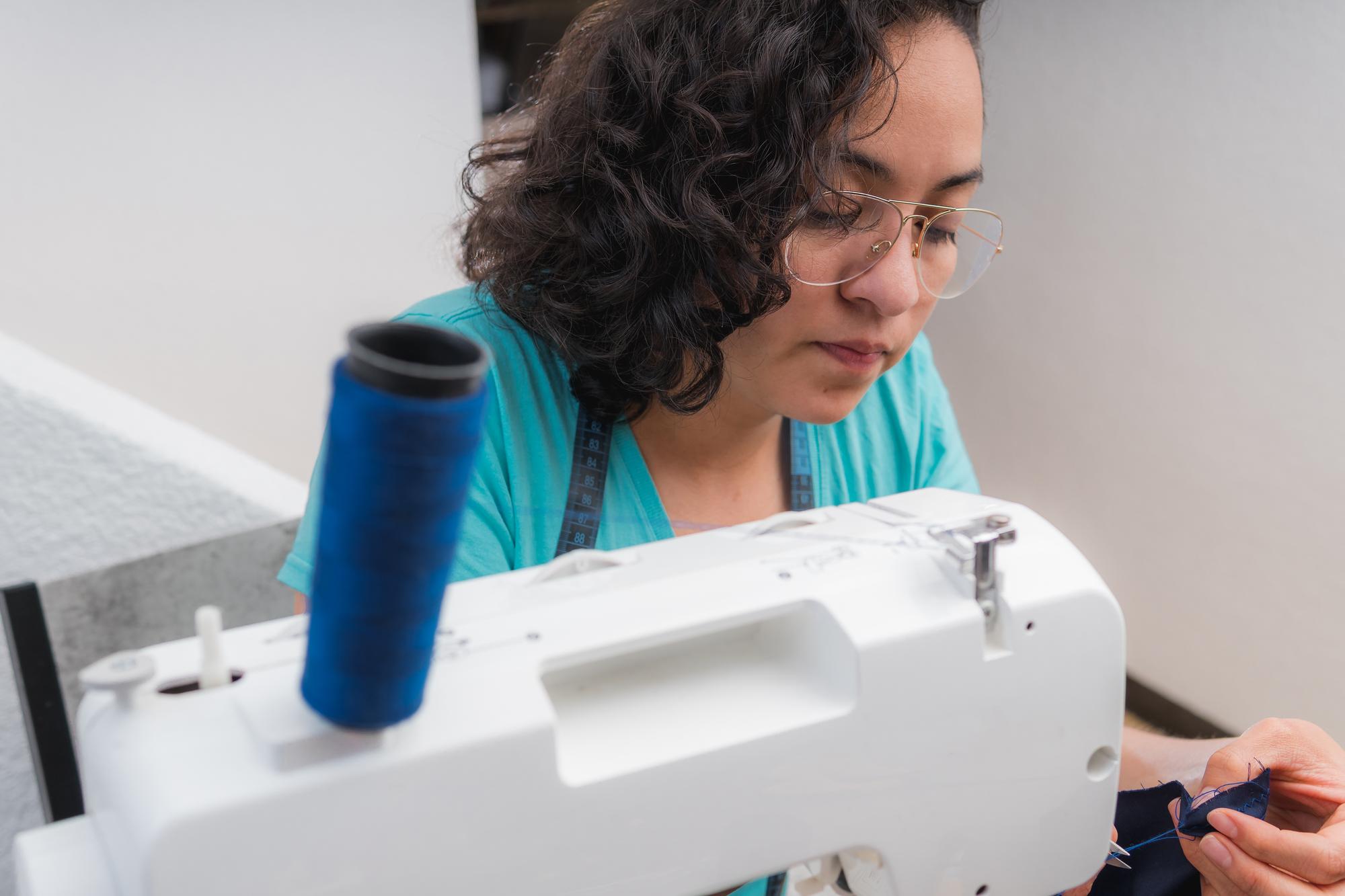 worker holding embroidered patch near sewing machine